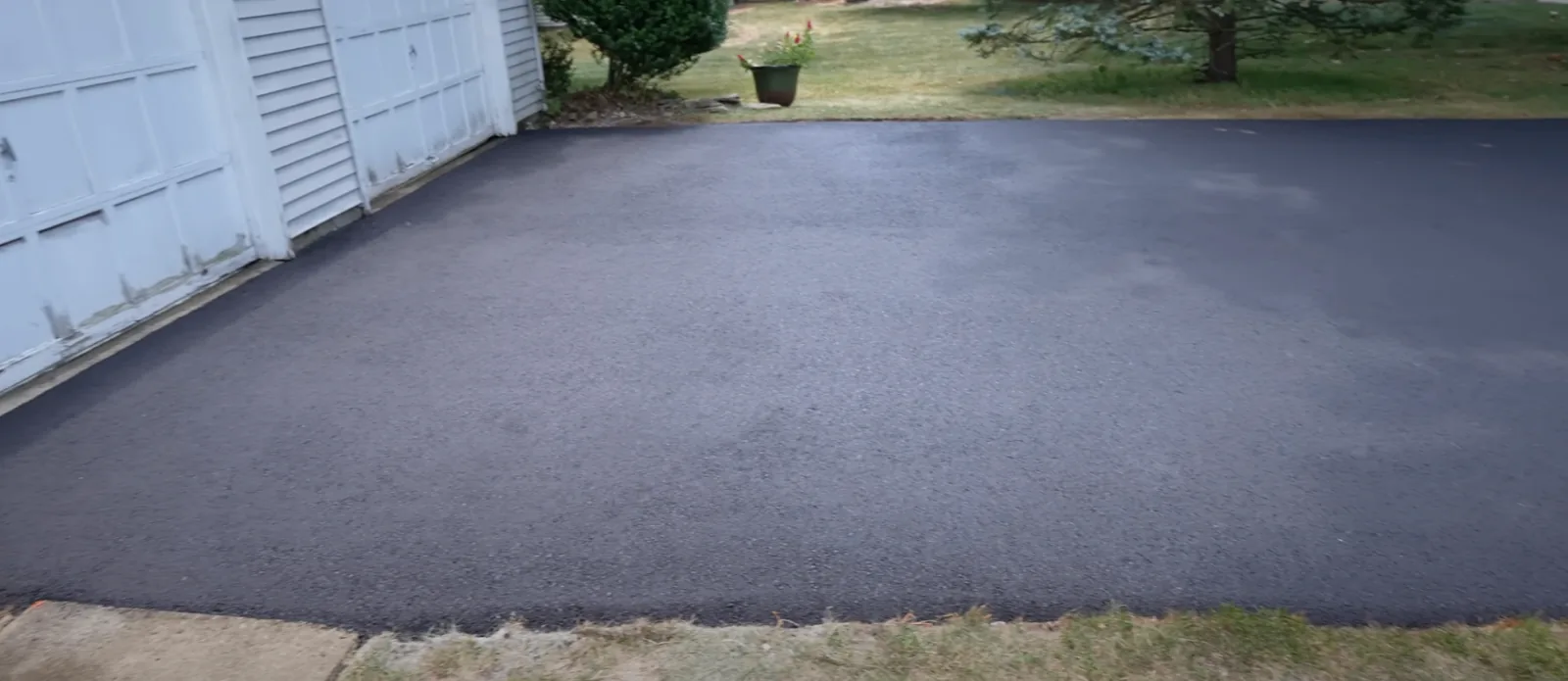 Dark finished driveway outside a garage