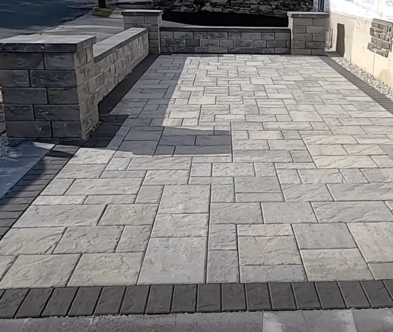 Gray paver patio with a low stone wall