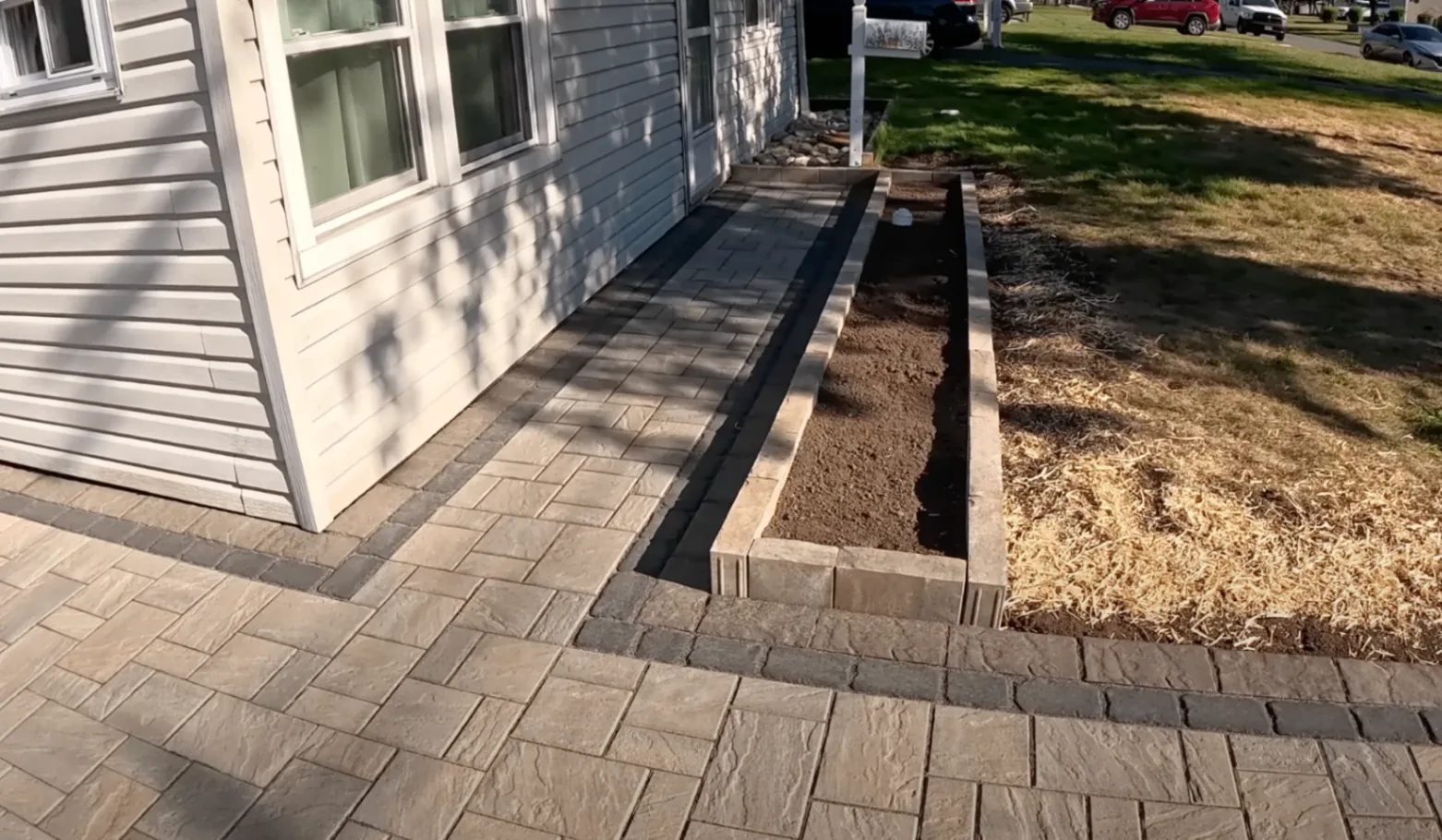 Paver walkway and raised border beside a house